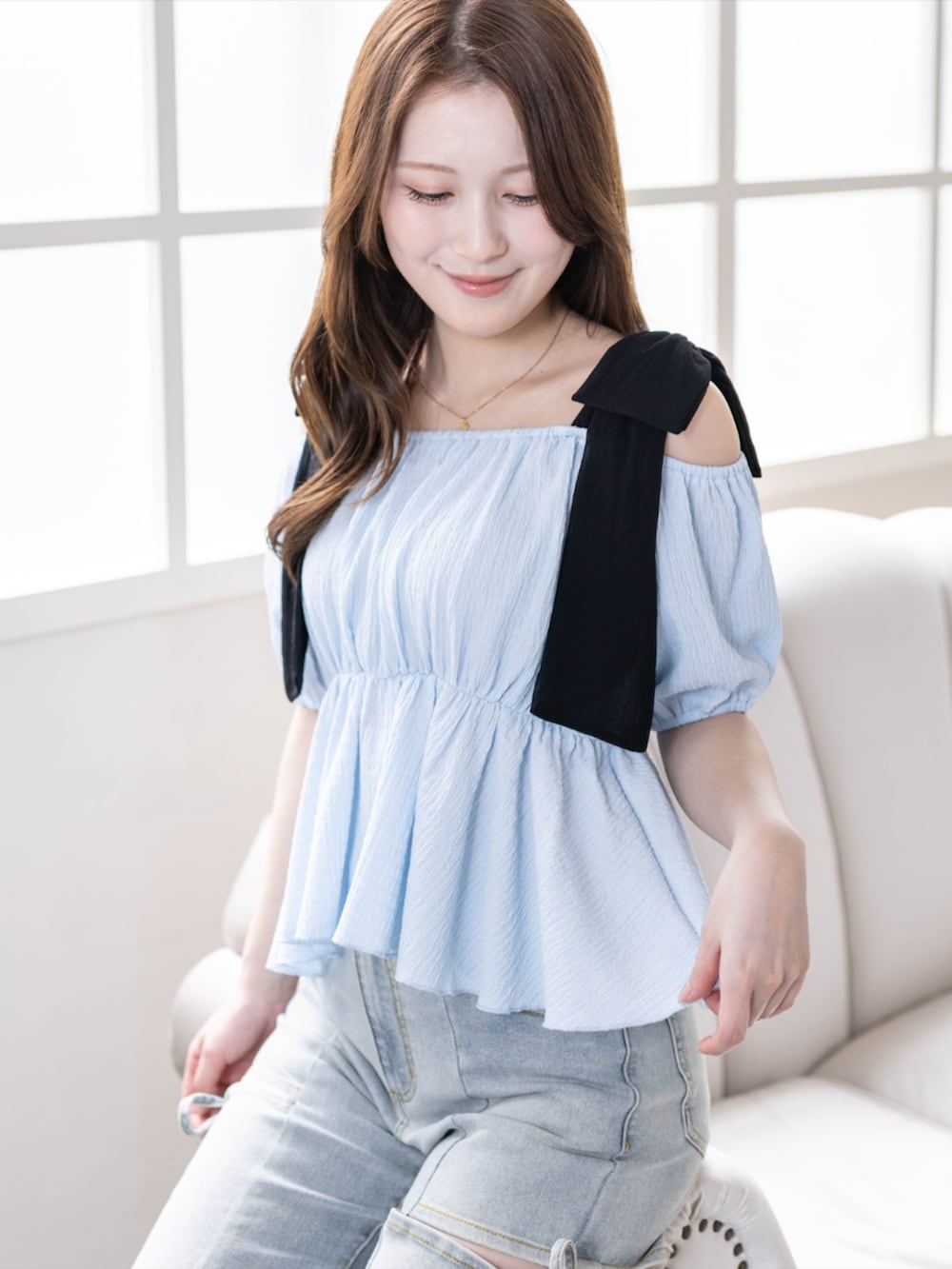 ブラック系のハンドバッグ、ブラック系のパンプス、ブルー系のデニムパンツを着用したレディースの春コーディネートの3枚目の写真
