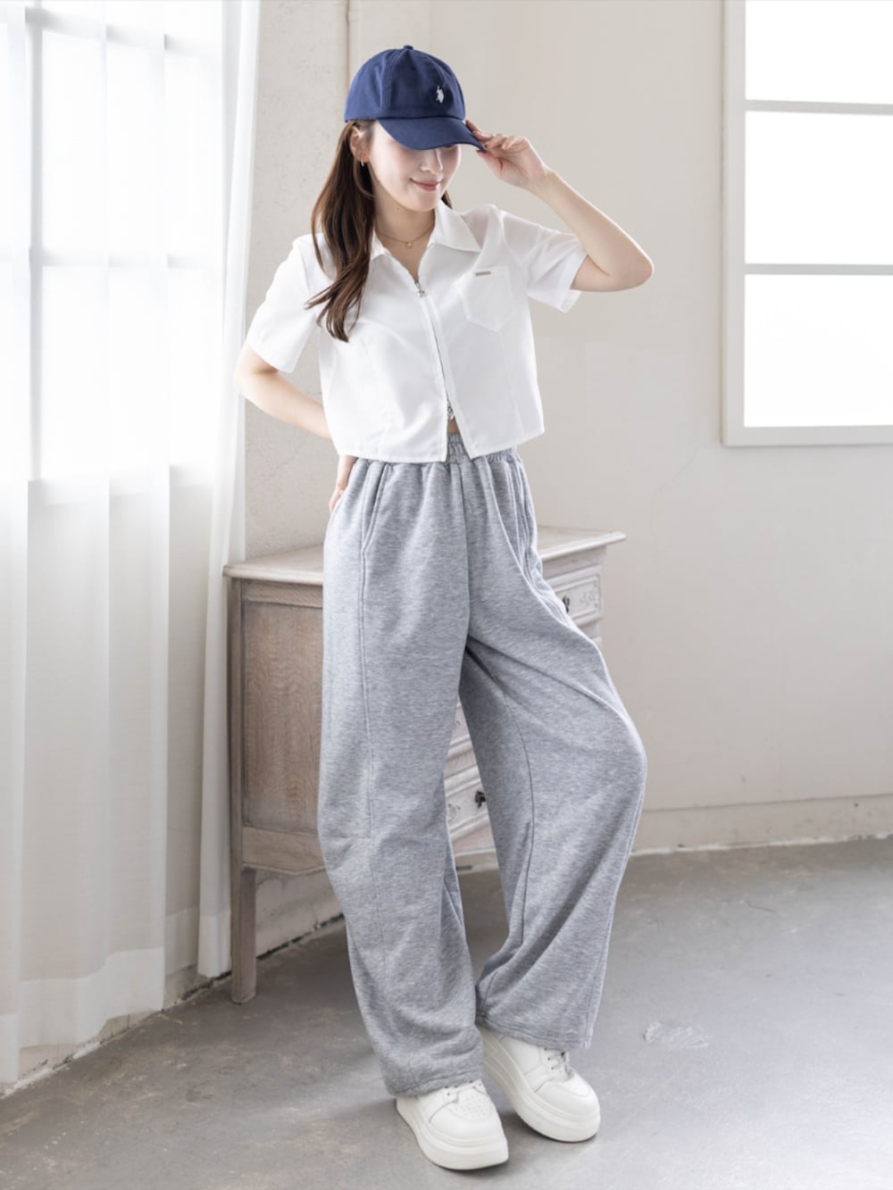 グレー系のスウェットパンツ、ホワイト系のシャツ/ブラウス、ブルー系のキャップを着用したレディースの春コーディネートの2枚目の写真