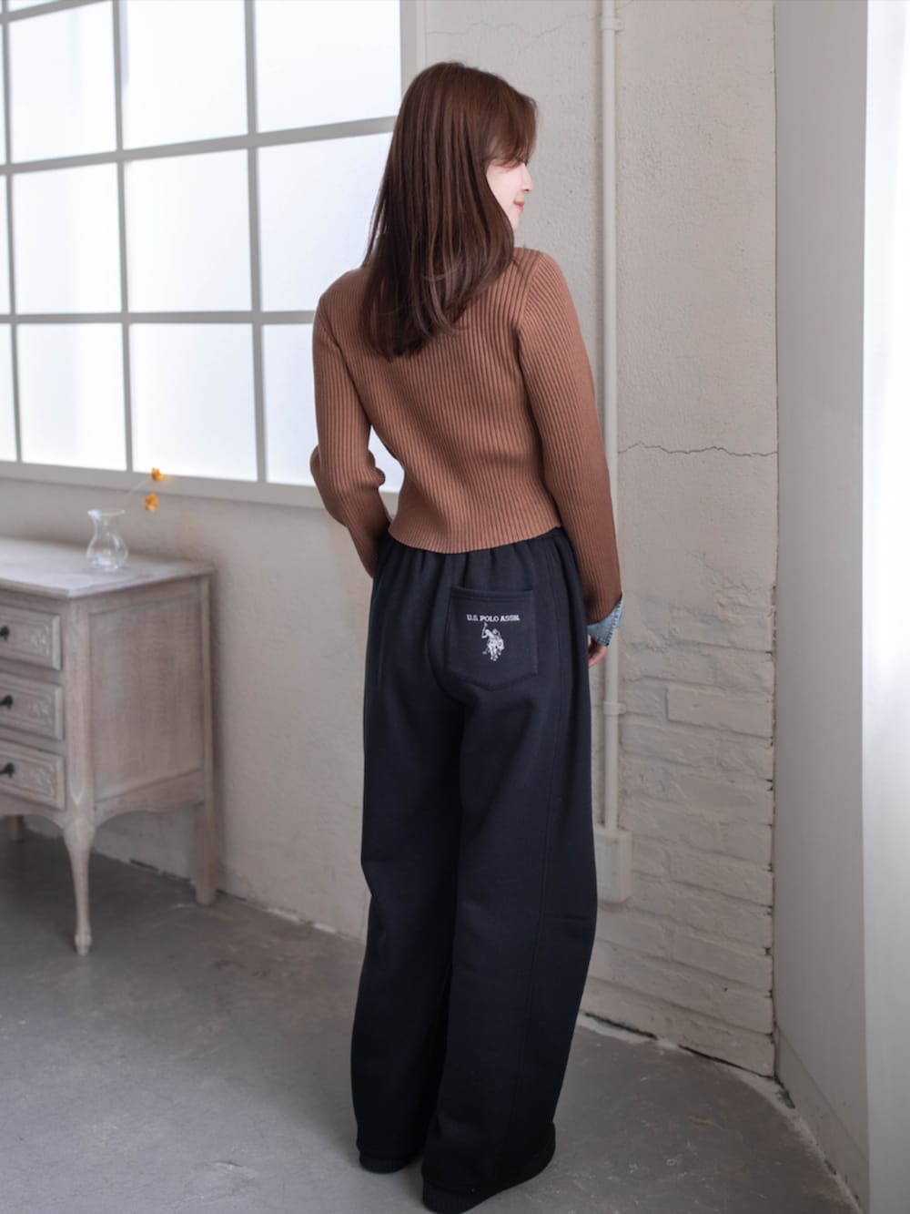 ブラック系のスウェットパンツ、ブラウン系のニット/セーター、ブラック系のスニーカーを着用したレディースの秋コーディネートの2枚目の写真