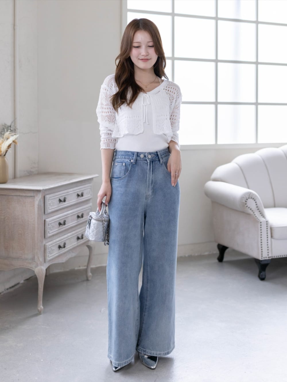 シルバー系のパンプス、ブルー系のデニムパンツ、ホワイト系のニット/セーターを着用したレディースの春コーディネートの3枚目の写真