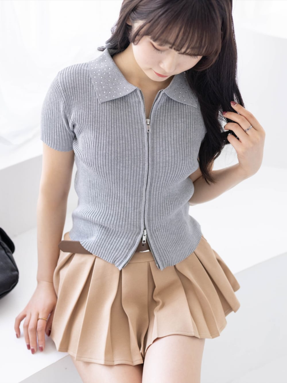 ブラック系のブーツ、ベージュ系のスカート、ブラック系のハンドバッグを着用したレディースの春コーディネートの4枚目の写真