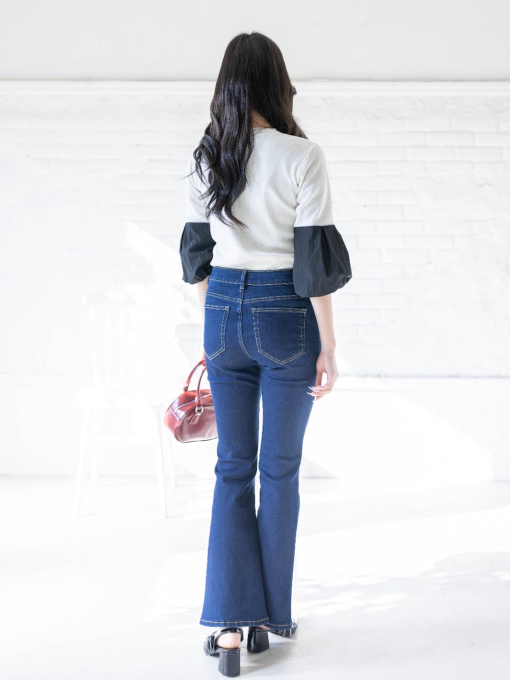 ブラック系のパンプス、ホワイト系のニット/セーター、ブルー系のデニムパンツを着用したレディースの春コーディネートの2枚目の写真