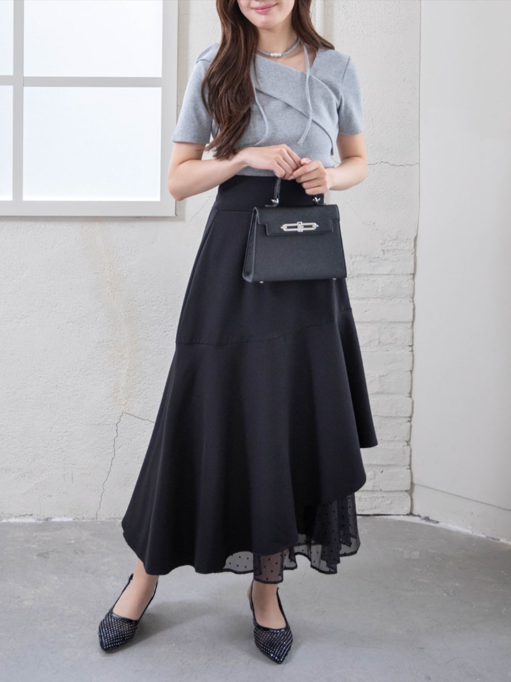 ブラック系のハンドバッグ、ブラック系のパンプス、グレー系のTシャツ/カットソーを着用したレディースの夏コーディネートの3枚目の写真