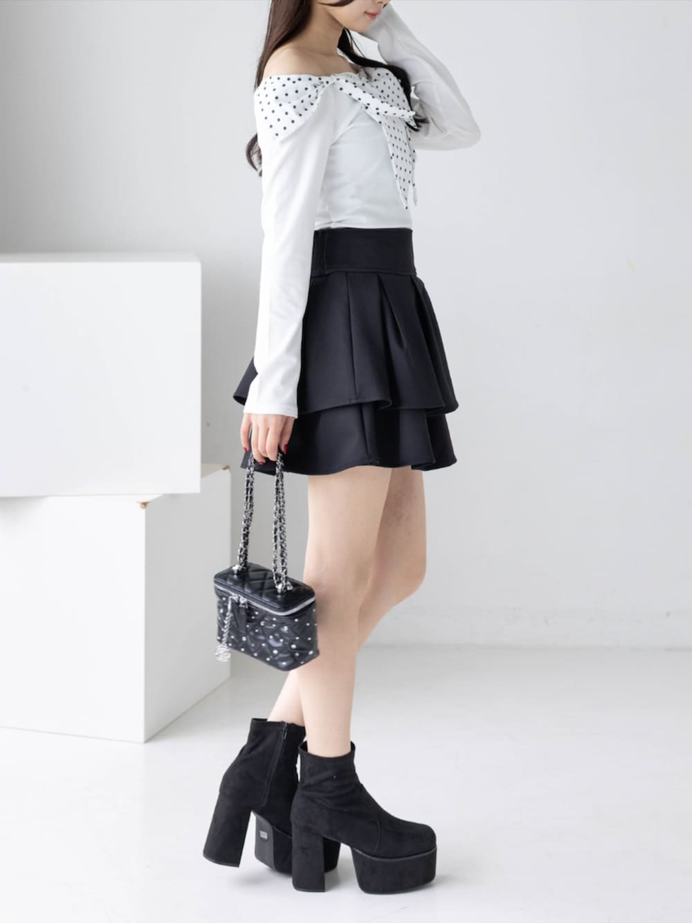 ブラック系のブーツ、ホワイト系のTシャツ/カットソー、ブラック系のスカートを着用したレディースの秋コーディネートの2枚目の写真