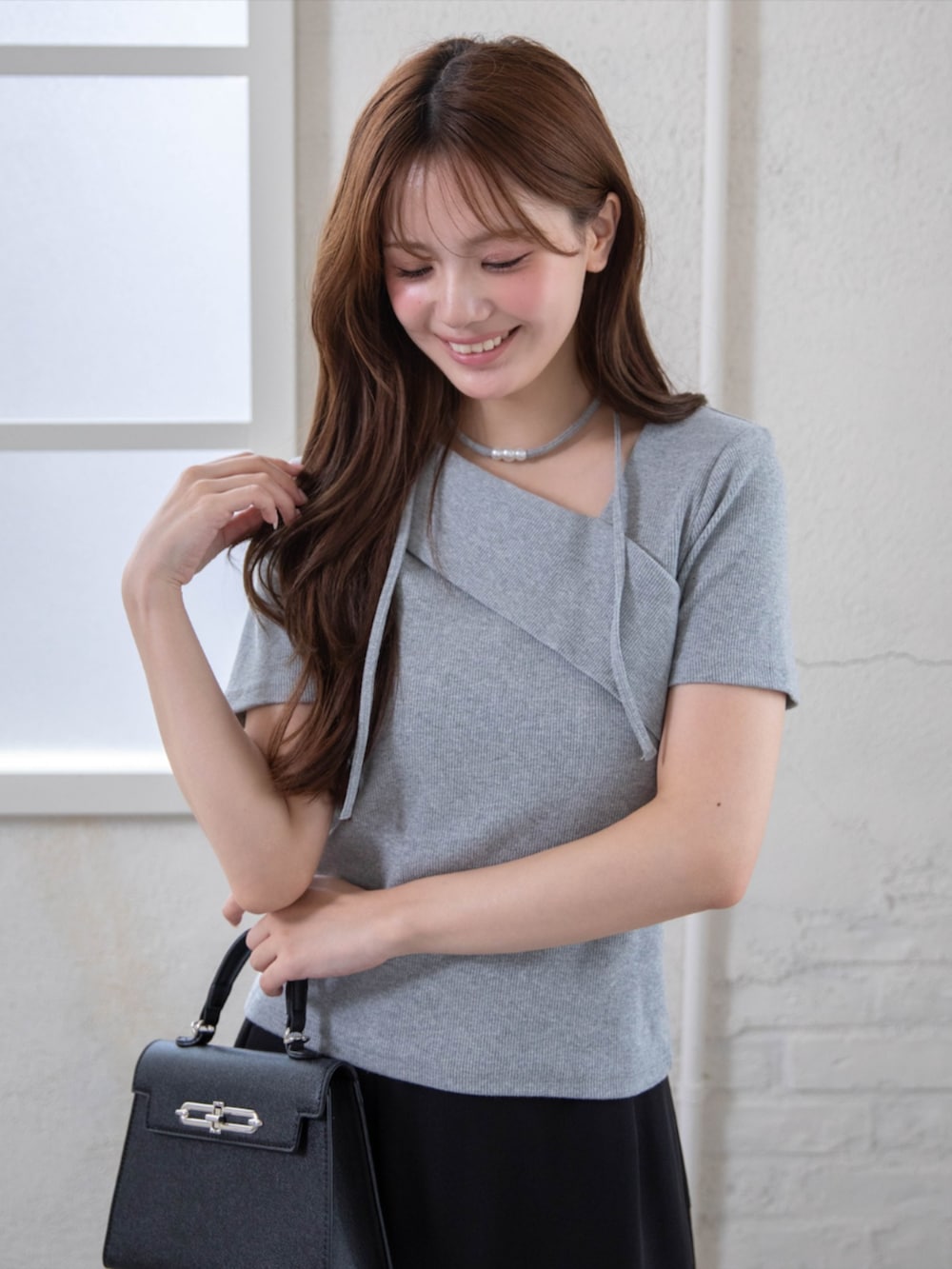 ブラック系のハンドバッグ、ブラック系のパンプス、グレー系のTシャツ/カットソーを着用したレディースの夏コーディネートの7枚目の写真
