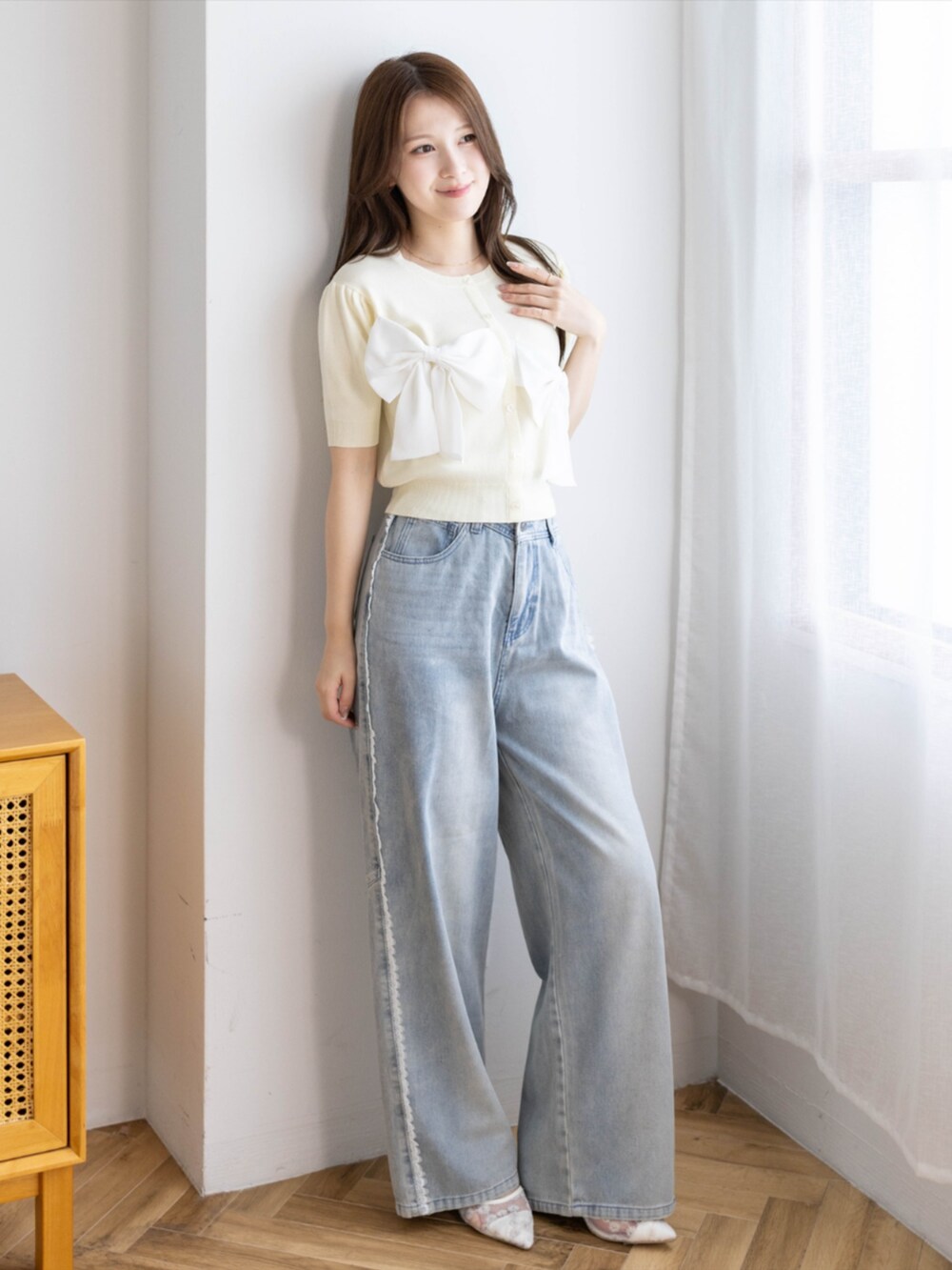 ブルー系のデニムパンツ、ホワイト系のパンプス、イエロー系のニット/セーターを着用したレディースの夏コーディネートの2枚目の写真