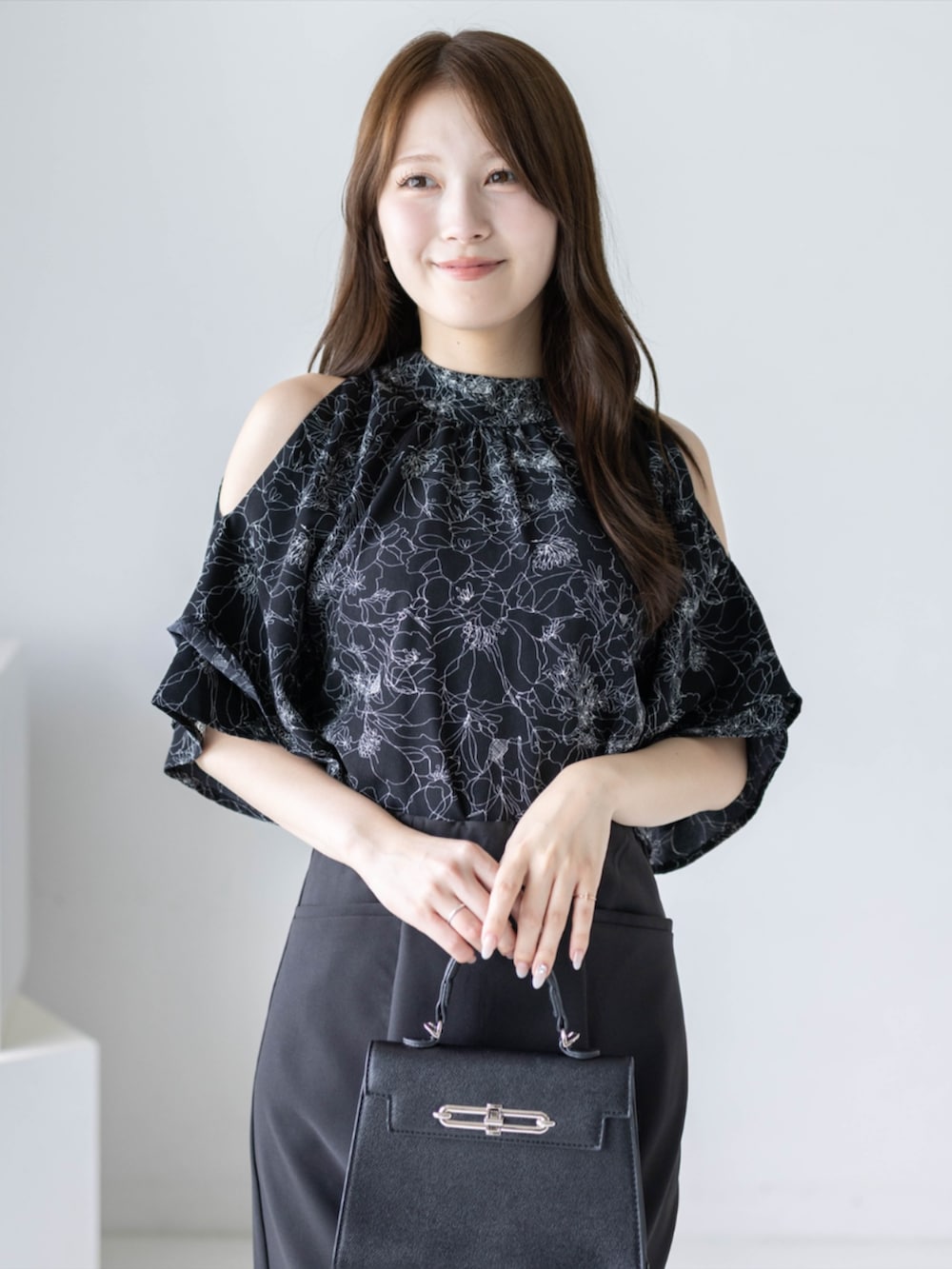 ブラック系のパンプス、ブラック系のハンドバッグ、ブラック系のスカートを着用したレディースの夏コーディネートの5枚目の写真