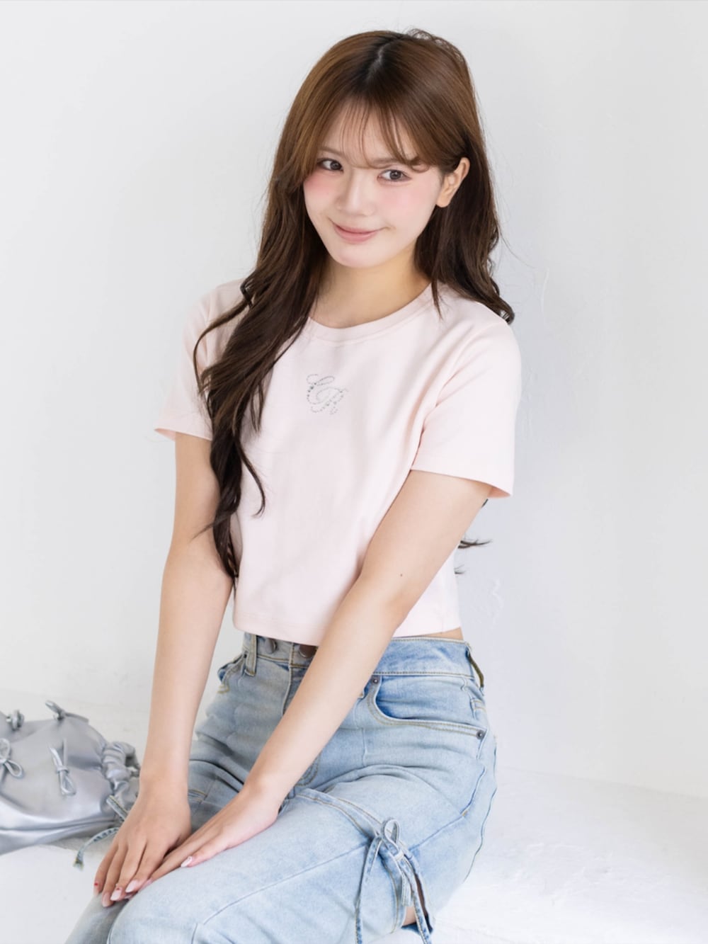 シルバー系のパンプス、ブルー系のデニムパンツ、ホワイト系のショルダーバッグを着用したレディースの夏コーディネートの6枚目の写真