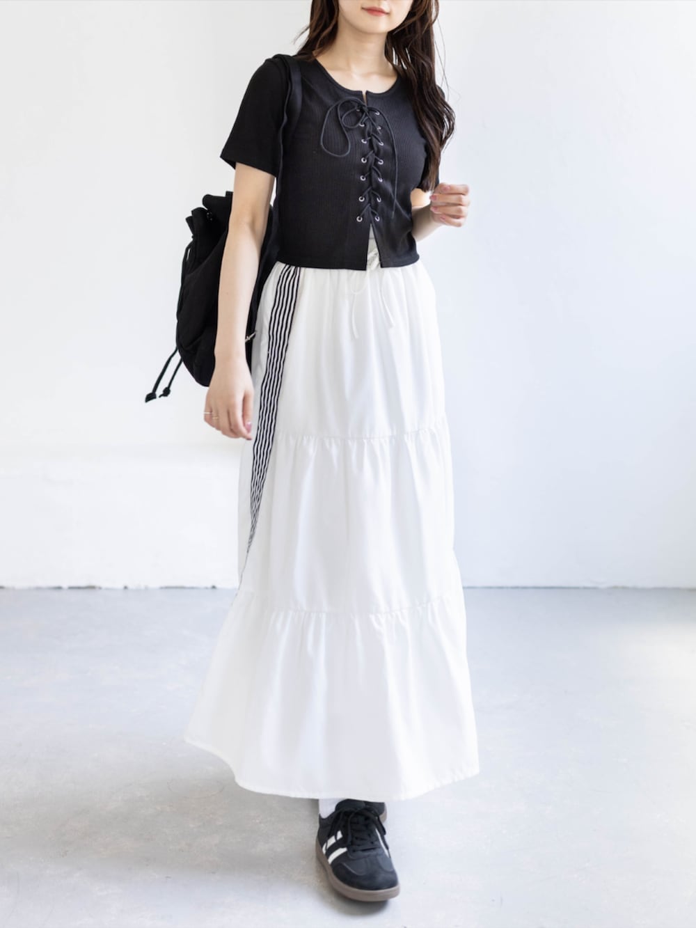ブラック系のスニーカー、ホワイト系のスカート、ブラック系のTシャツ/カットソーを着用したレディースの夏コーディネートの4枚目の写真