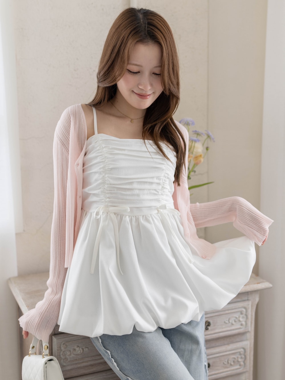 ホワイト系のチュニック、ホワイト系のパンプス、ピンク系のカーディガン/ボレロを着用したレディースの春コーディネートの3枚目の写真