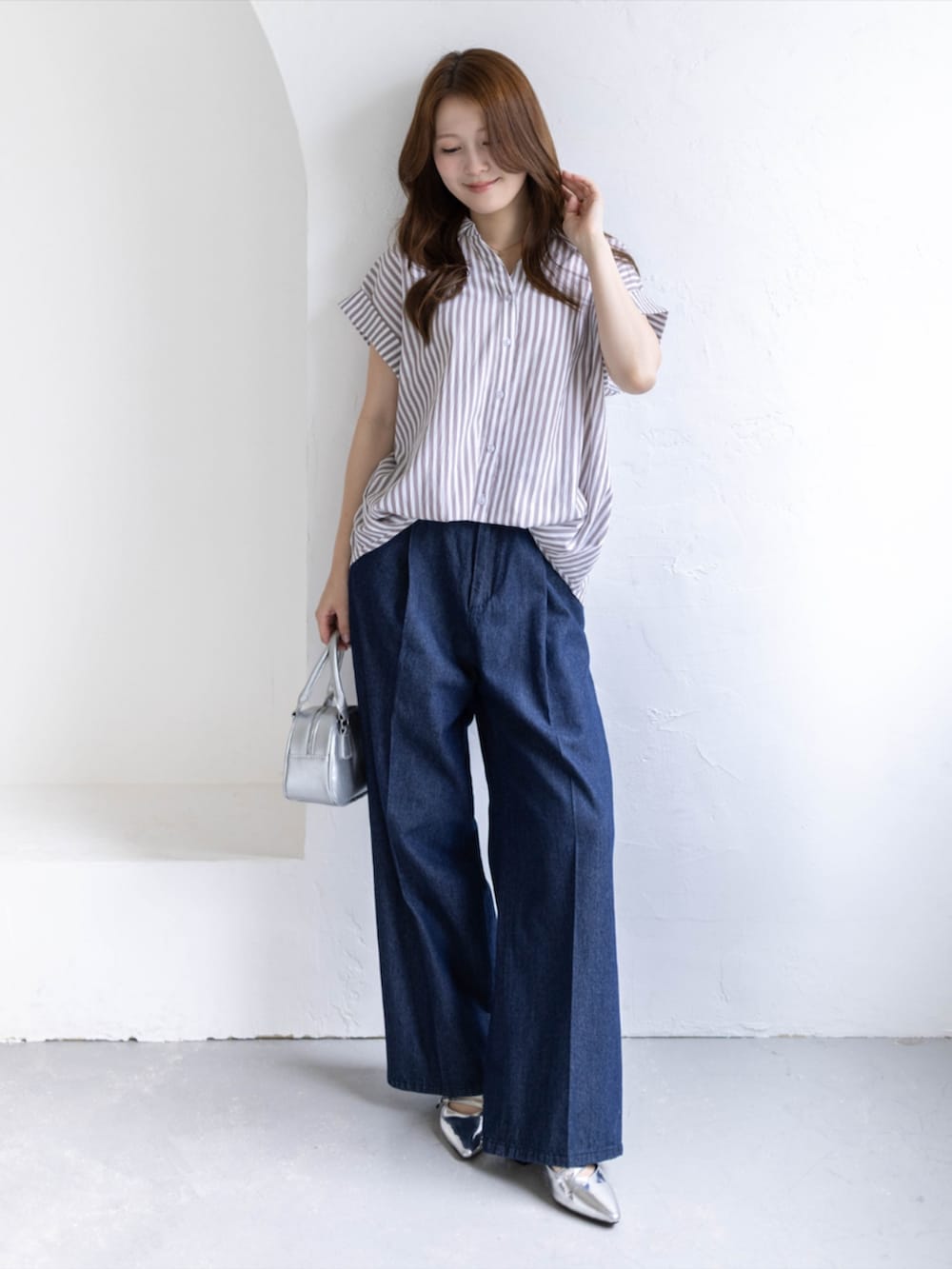 シルバー系のパンプス、ベージュ系のシャツ/ブラウス、ブルー系のデニムパンツを着用したレディースの夏コーディネートの2枚目の写真