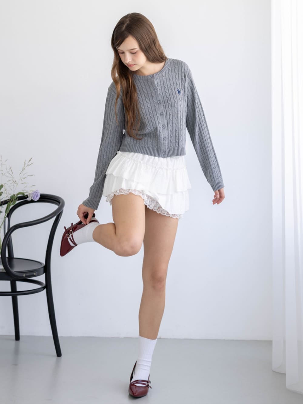 レッド系のパンプス、グレー系のカーディガン/ボレロ、ホワイト系のスカートを着用したレディースの秋コーディネートの2枚目の写真
