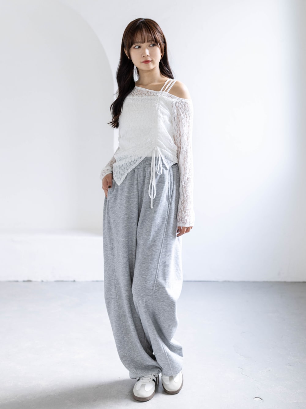 ホワイト系のスニーカー、グレー系のスウェットパンツ、ホワイト系のアンサンブルを着用したレディースの春コーディネートの3枚目の写真