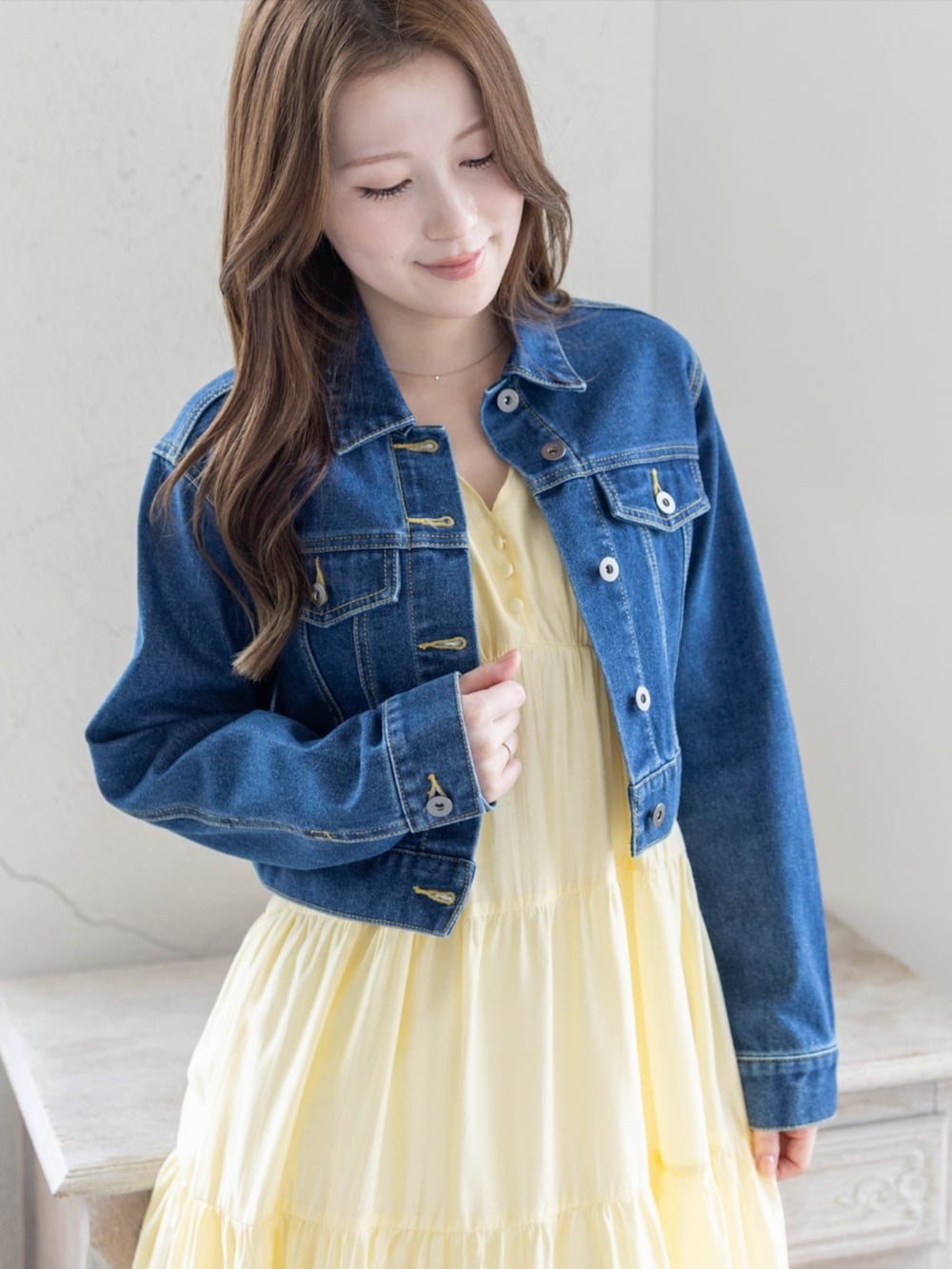 シルバー系のパンプス、ブルー系のデニムジャケット、イエロー系のワンピースを着用したレディースの春コーディネートの4枚目の写真