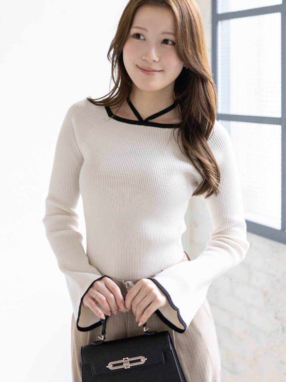 ホワイト系のニット/セーター、ベージュ系のスラックス、ブラック系のハンドバッグを着用したレディースの春コーディネートの5枚目の写真