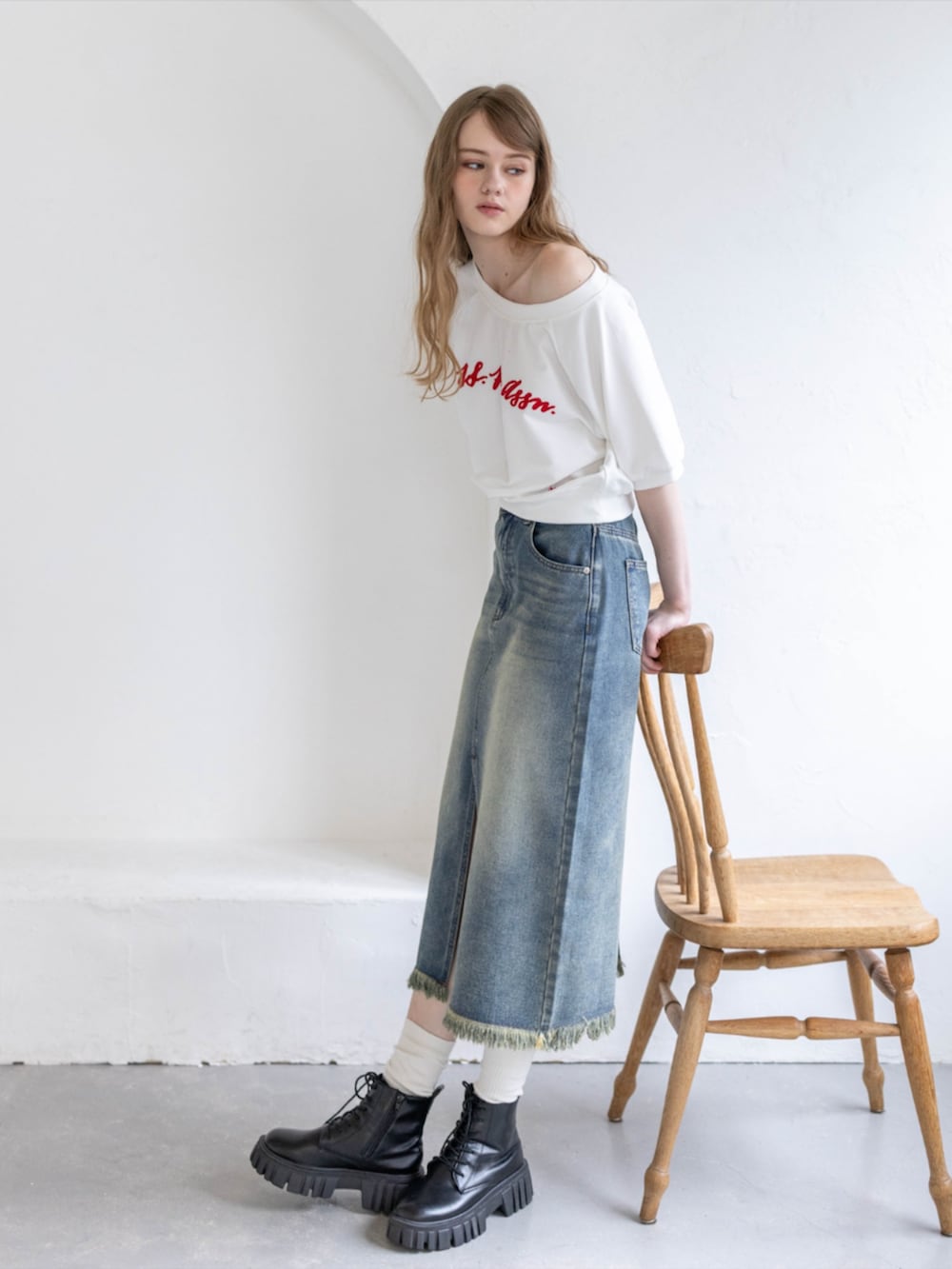 ブラック系のブーツ、ホワイト系のTシャツ/カットソー、ブルー系のデニムスカートを着用したレディースの夏コーディネートの2枚目の写真