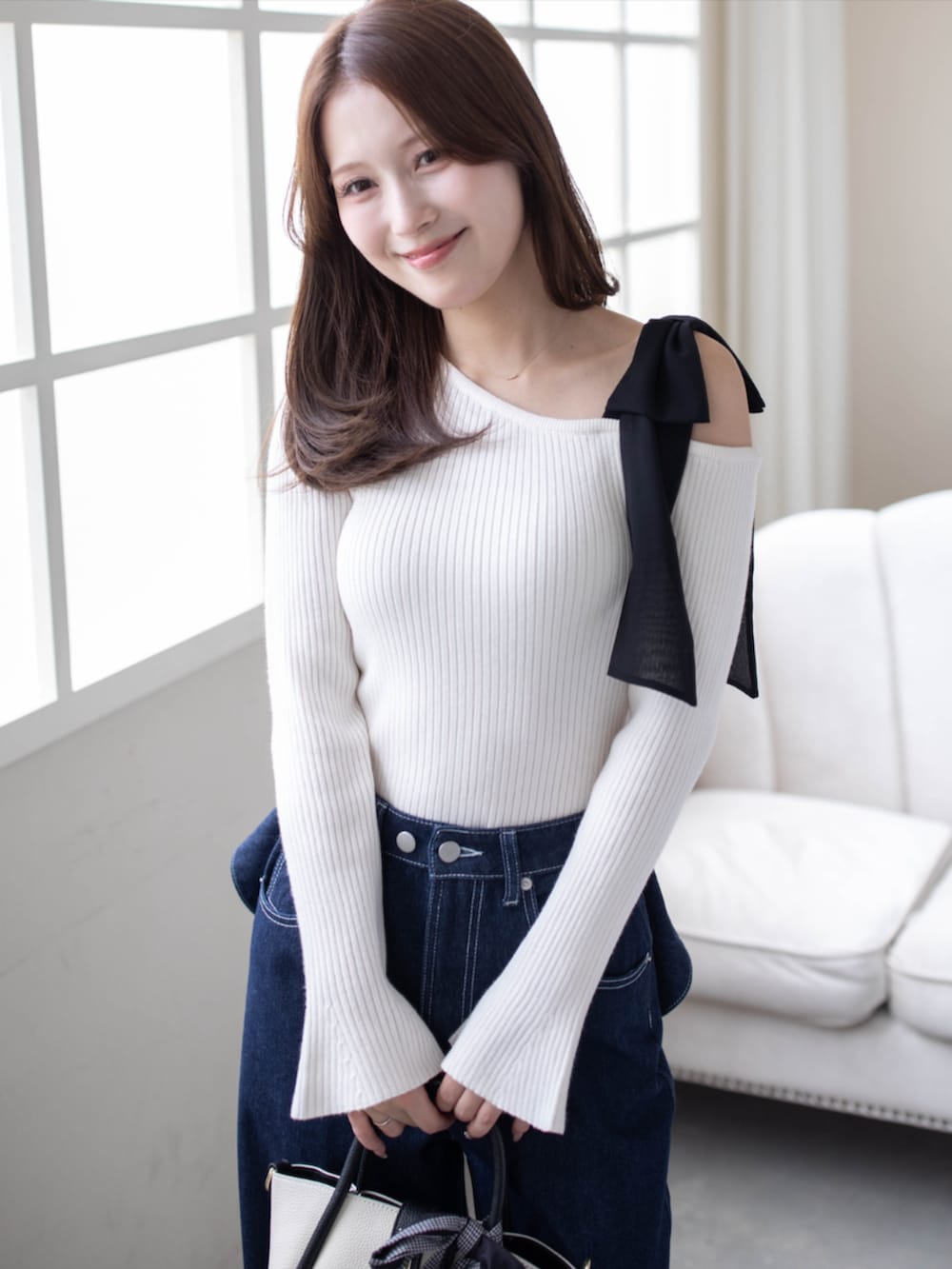 ブラック系のハンドバッグ、ブルー系のデニムパンツ、ブラック系のパンプスを着用したレディースの秋コーディネートの5枚目の写真