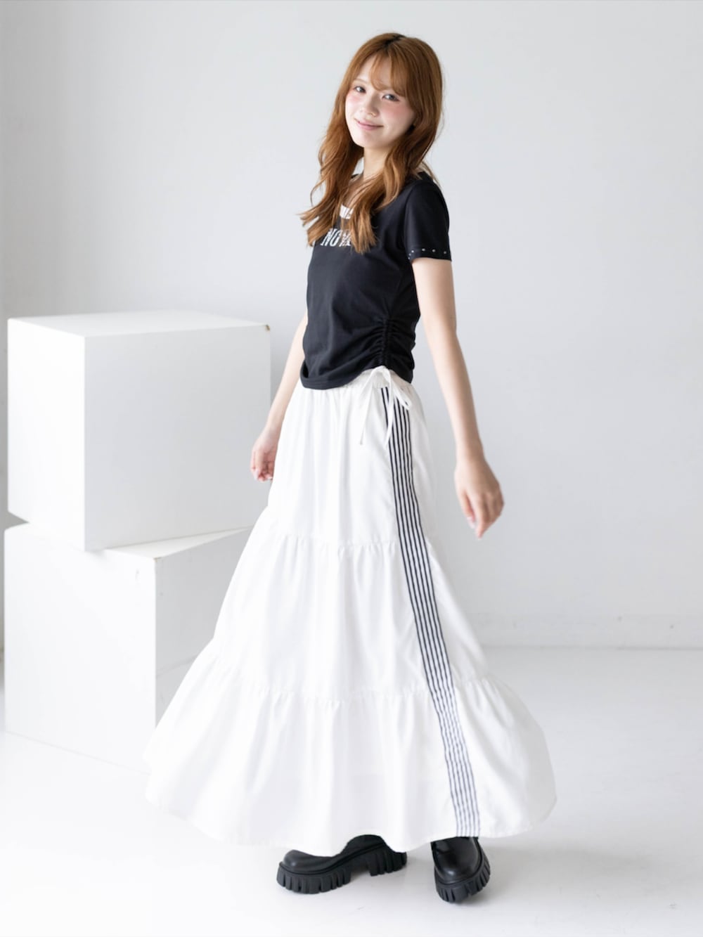 ブラック系のブーツ、ホワイト系のスカート、ブラック系のTシャツ/カットソーを着用したレディースの夏コーディネートの2枚目の写真