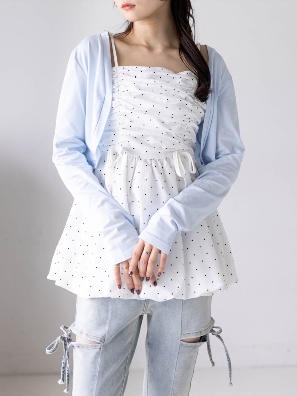 ホワイト系のチュニック、ホワイト系のパンプス、ブルー系のデニムパンツを着用したレディースの夏コーディネートの6枚目の写真
