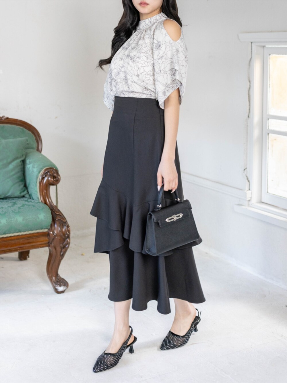 ブラック系のハンドバッグ、ブラック系のパンプス、ブラック系のスカートを着用したレディースの春コーディネートの2枚目の写真