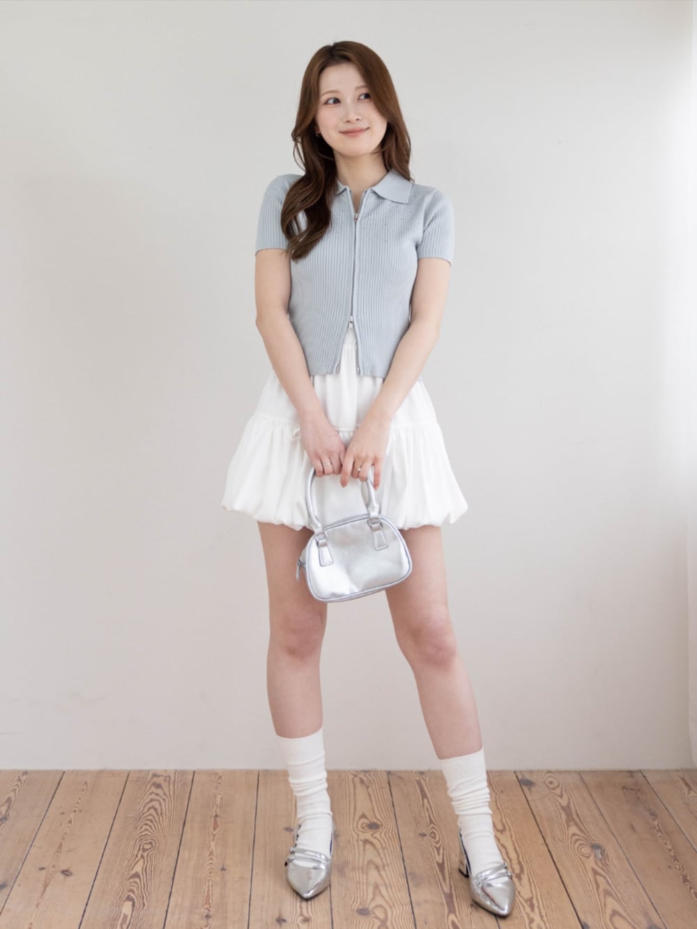 シルバー系のパンプス、ホワイト系のスカート、グレー系のニット/セーターを着用したレディースの春コーディネートの2枚目の写真