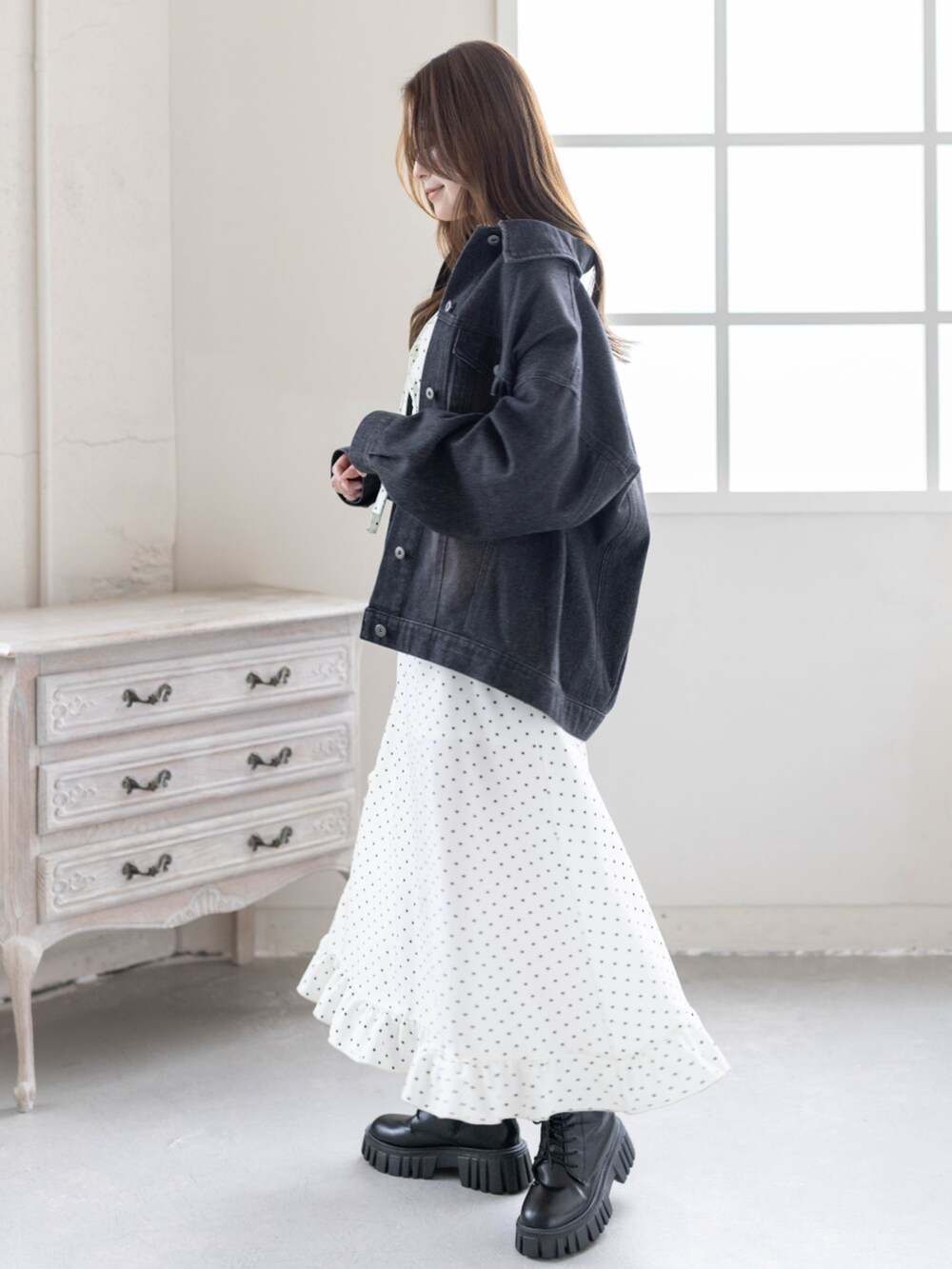 ブラック系のブーツ、ブラック系のデニムジャケット、ホワイト系のワンピースを着用したレディースの春コーディネートの2枚目の写真