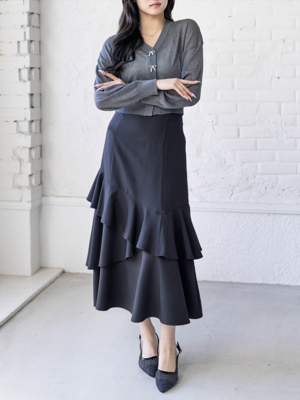 ブラック系のパンプス、ブラック系のスカート、グレー系のカーディガン/ボレロを着用したレディースの春コーディネートの2枚目の写真