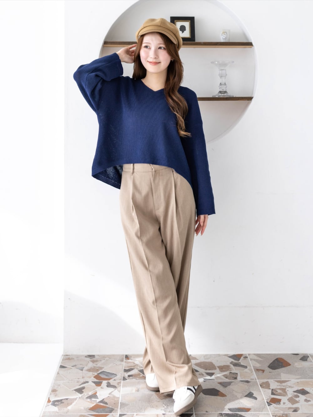 ホワイト系のスニーカー、ベージュ系のスラックス、ブルー系のニット/セーターを着用したレディースの春コーディネートの2枚目の写真