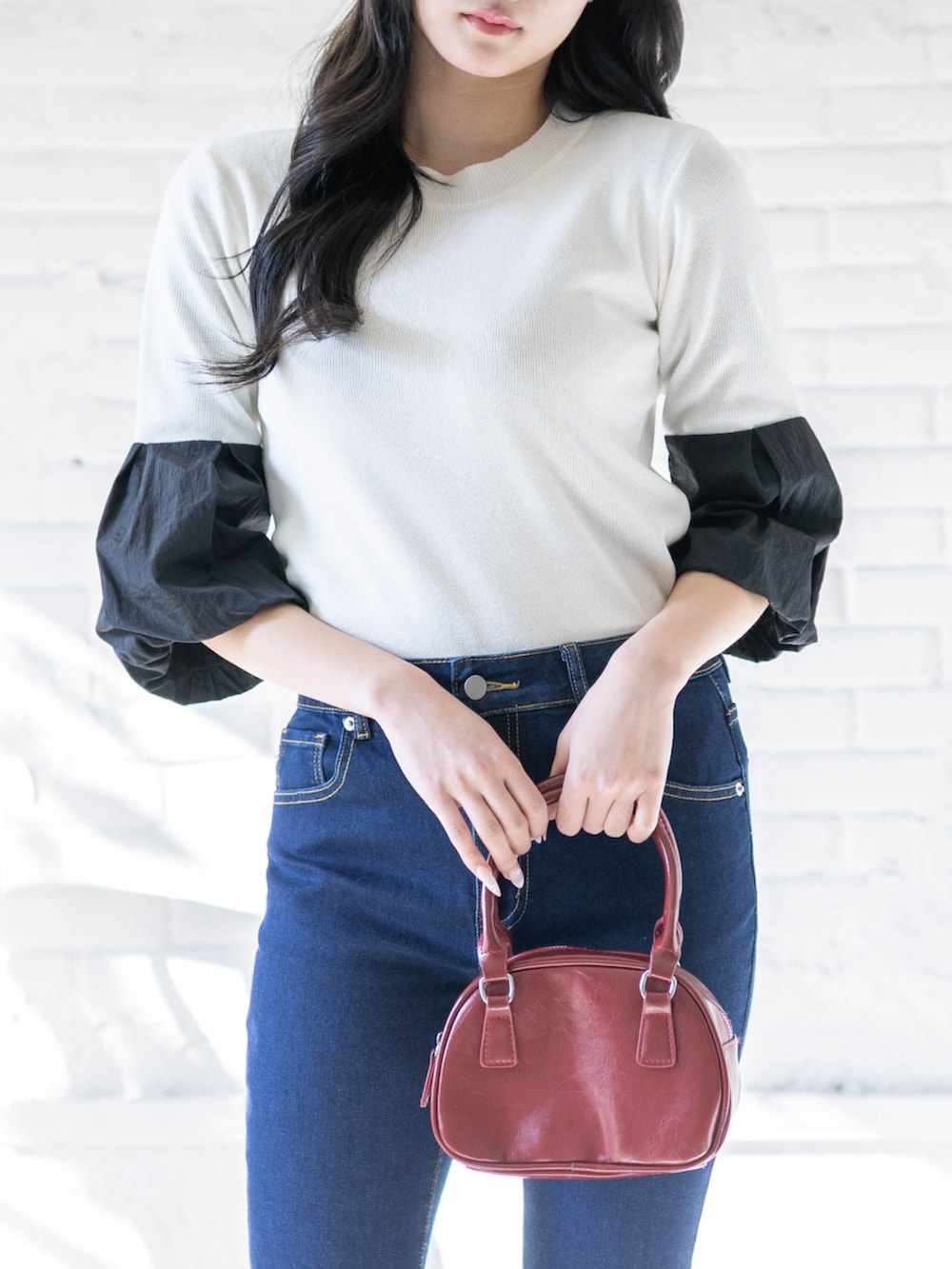 ブラック系のパンプス、ホワイト系のニット/セーター、ブルー系のデニムパンツを着用したレディースの春コーディネートの5枚目の写真