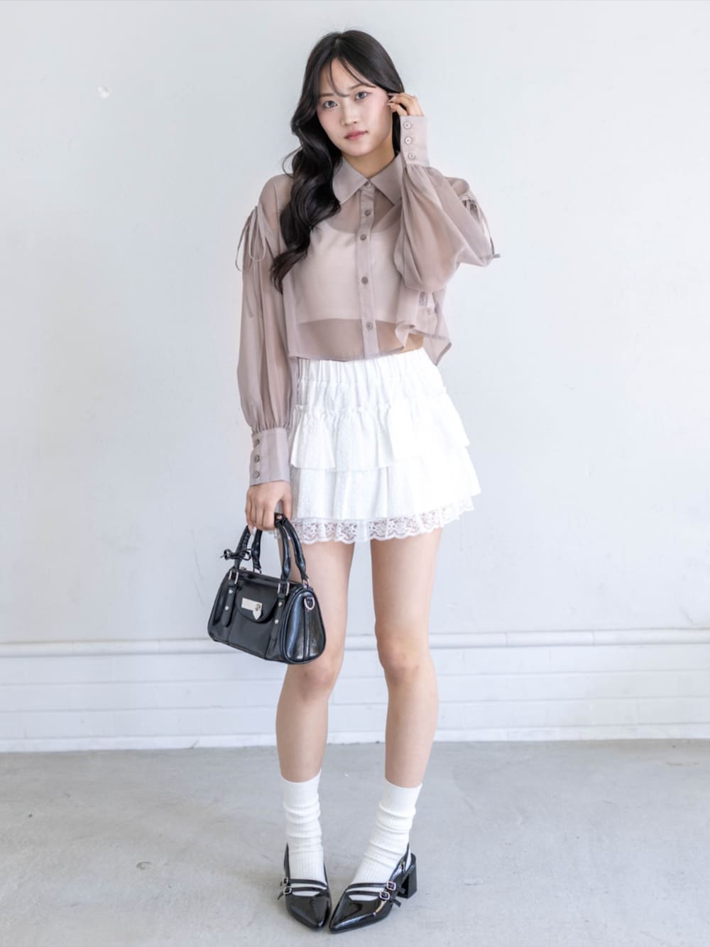 ブラック系のパンプス、ホワイト系のスカート、ブラック系のハンドバッグを着用したレディースの春コーディネートの2枚目の写真