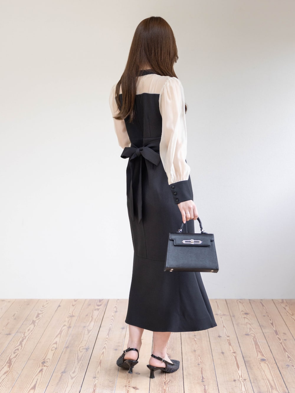 ブラック系のハンドバッグ、ブラック系のパンプス、ブラック系のワンピースを着用したレディースの春コーディネートの5枚目の写真