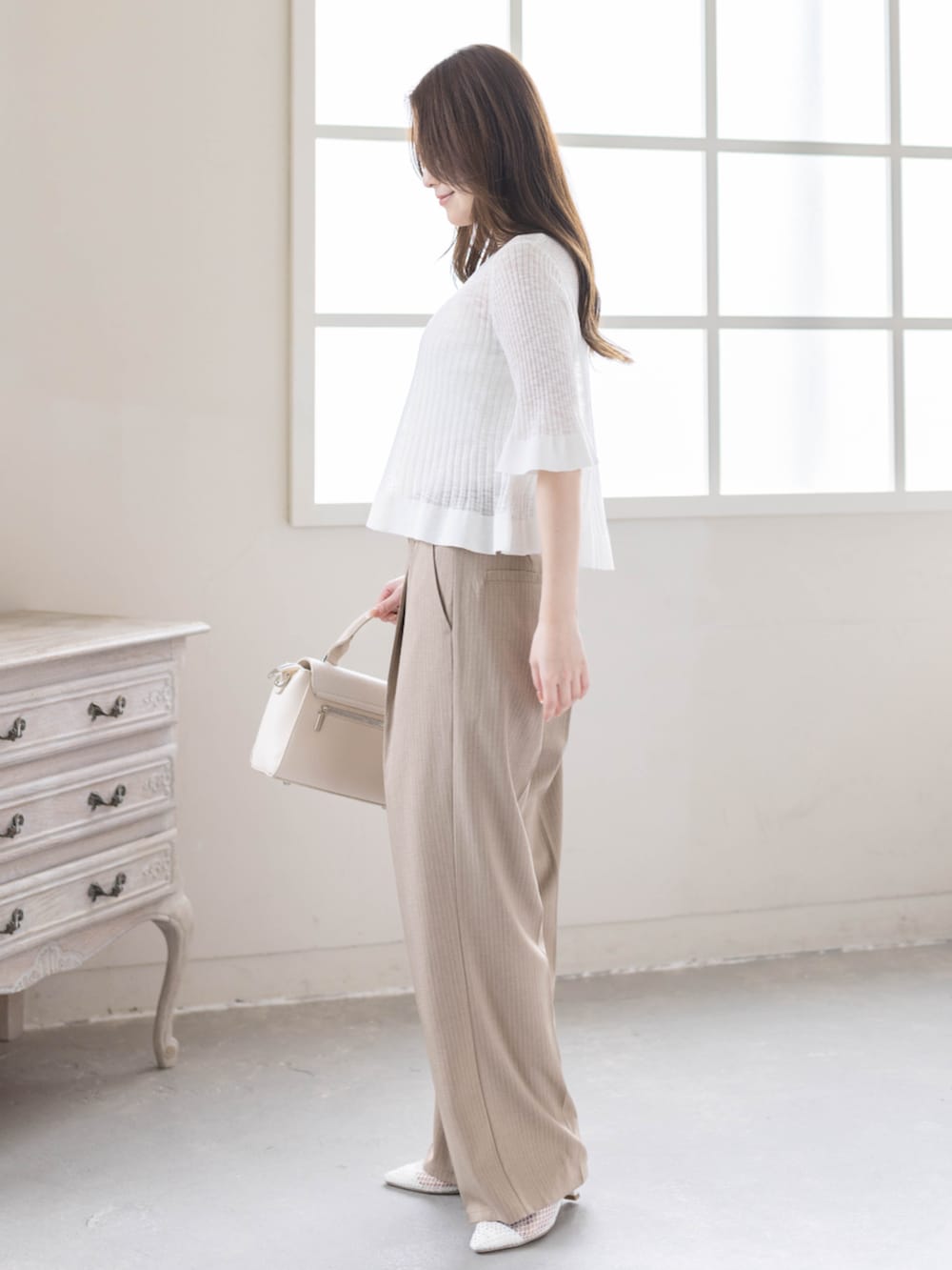 ベージュ系のスラックス、ホワイト系のパンプス、ホワイト系のカーディガン/ボレロを着用したレディースの春コーディネートの3枚目の写真