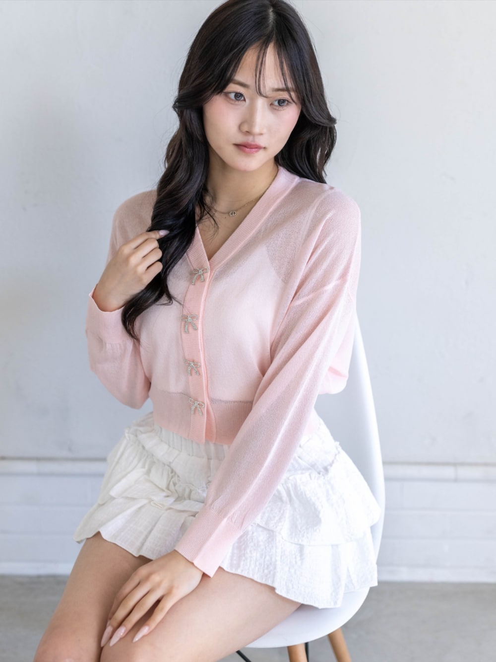 ホワイト系のスカート、ホワイト系のパンプス、ピンク系のカーディガン/ボレロを着用したレディースの春コーディネートの4枚目の写真