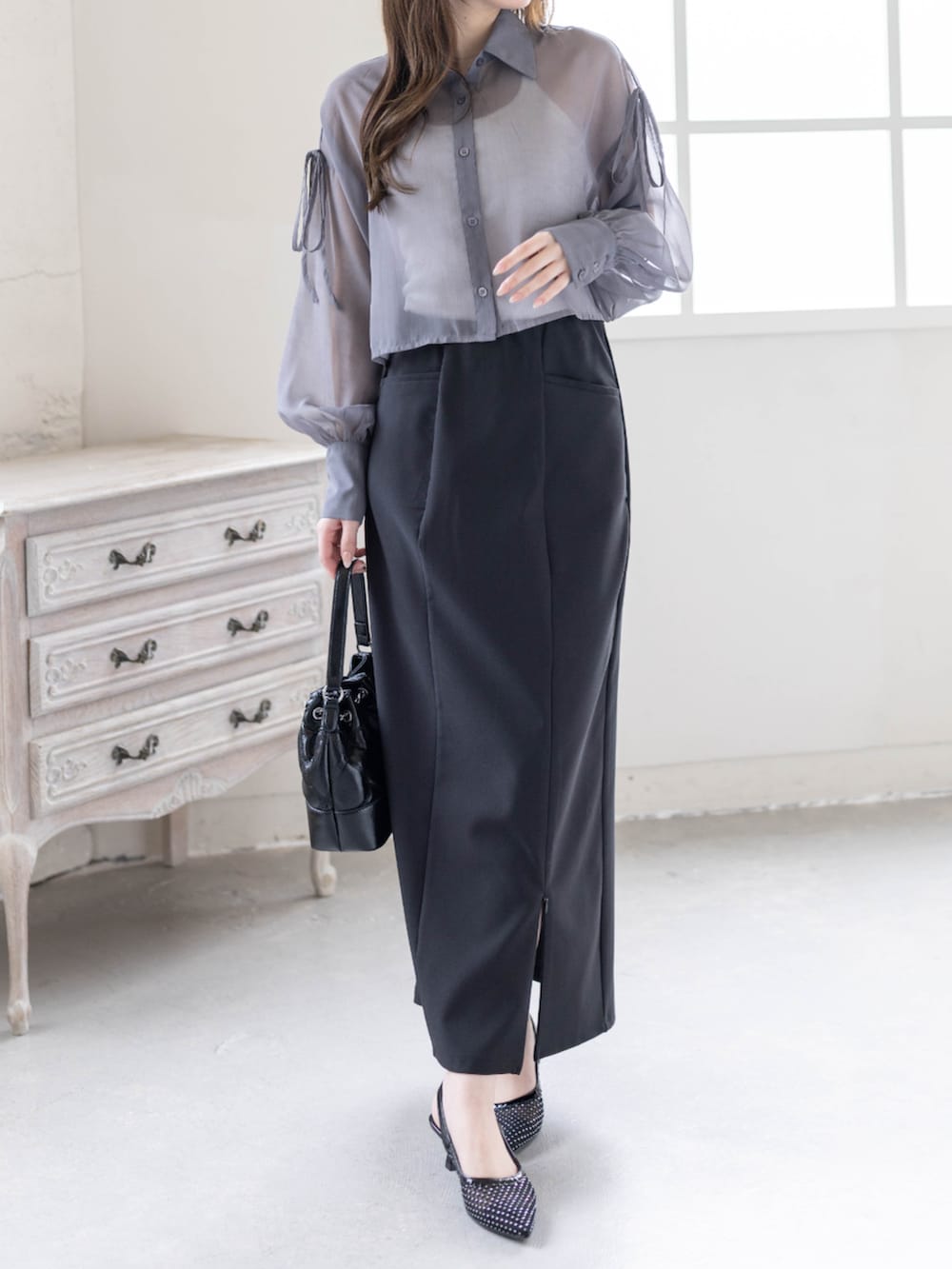 ブラック系のハンドバッグ、ブラック系のパンプス、ブラック系のスカートを着用したレディースの春コーディネートの3枚目の写真