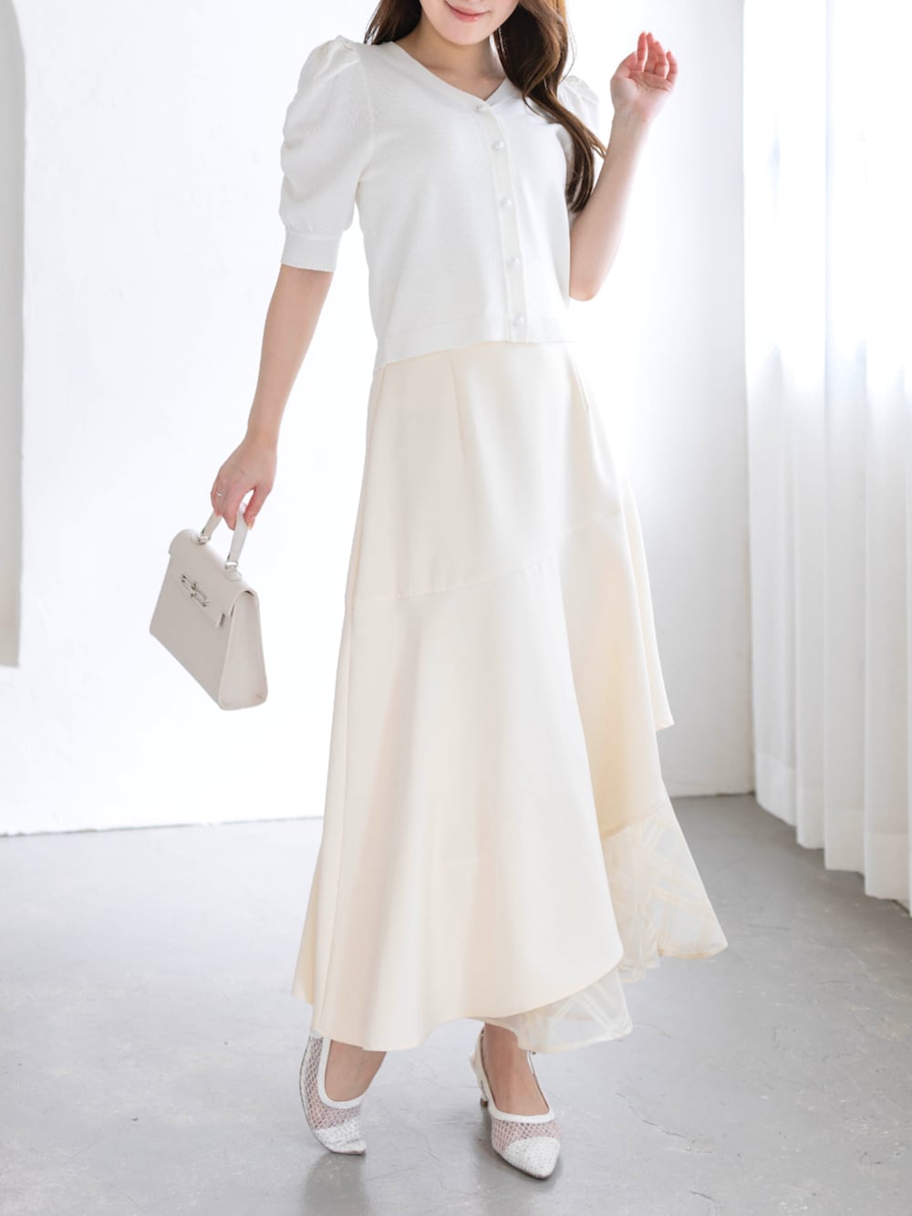 ホワイト系のスカート、ホワイト系のハンドバッグ、ホワイト系のパンプスを着用したレディースの春コーディネートの3枚目の写真