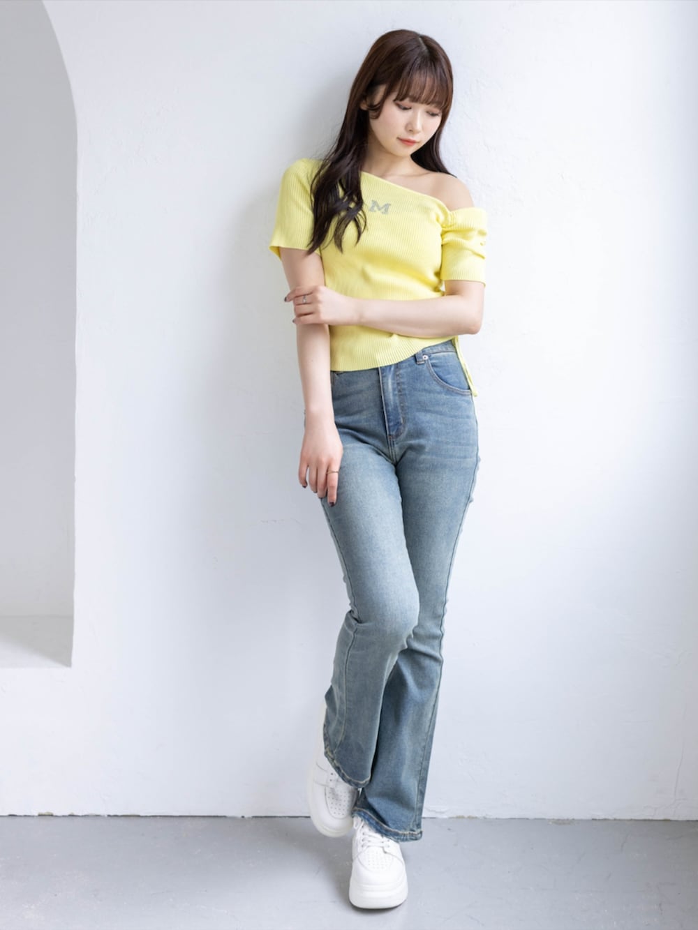 ホワイト系のスニーカー、ブルー系のデニムパンツ、イエロー系のニット/セーターを着用したレディースの春コーディネートの2枚目の写真