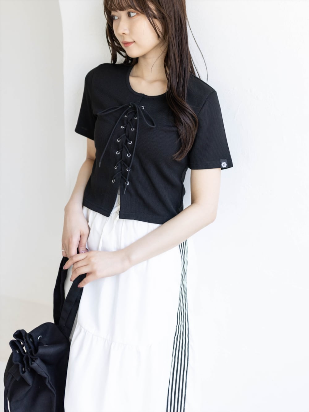 ブラック系のスニーカー、ホワイト系のスカート、ブラック系のTシャツ/カットソーを着用したレディースの夏コーディネートの6枚目の写真