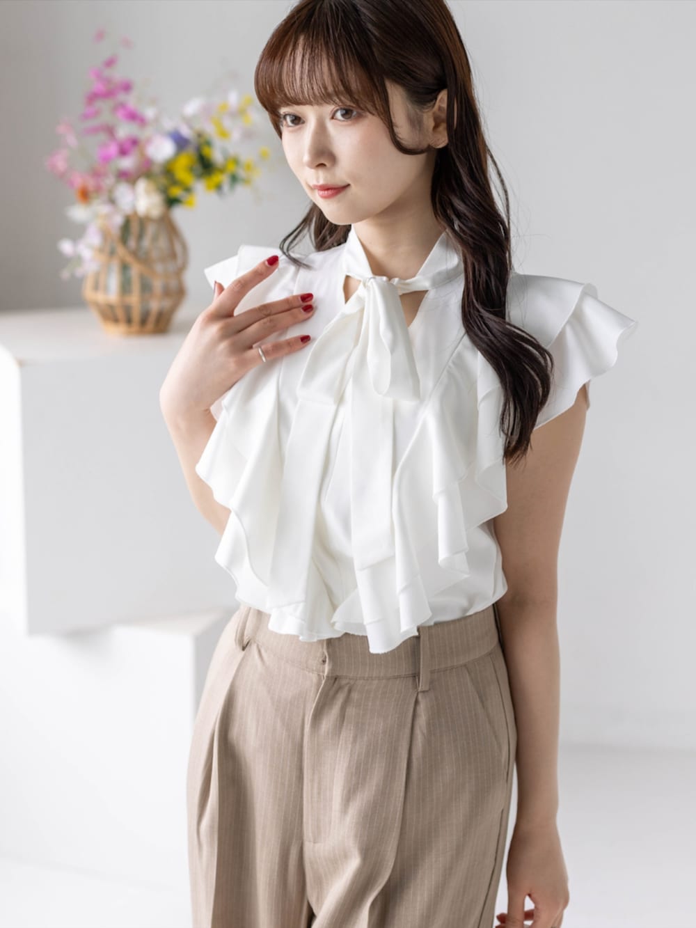 ベージュ系のスラックス、ホワイト系のハンドバッグ、ホワイト系のパンプスを着用したレディースの夏コーディネートの5枚目の写真