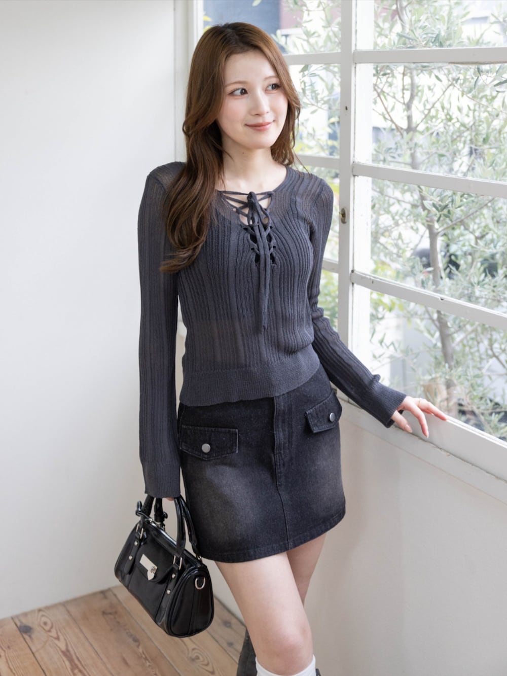 グレー系のブーツ、ブラック系のハンドバッグ、グレー系のニット/セーターを着用したレディースの春コーディネートの4枚目の写真