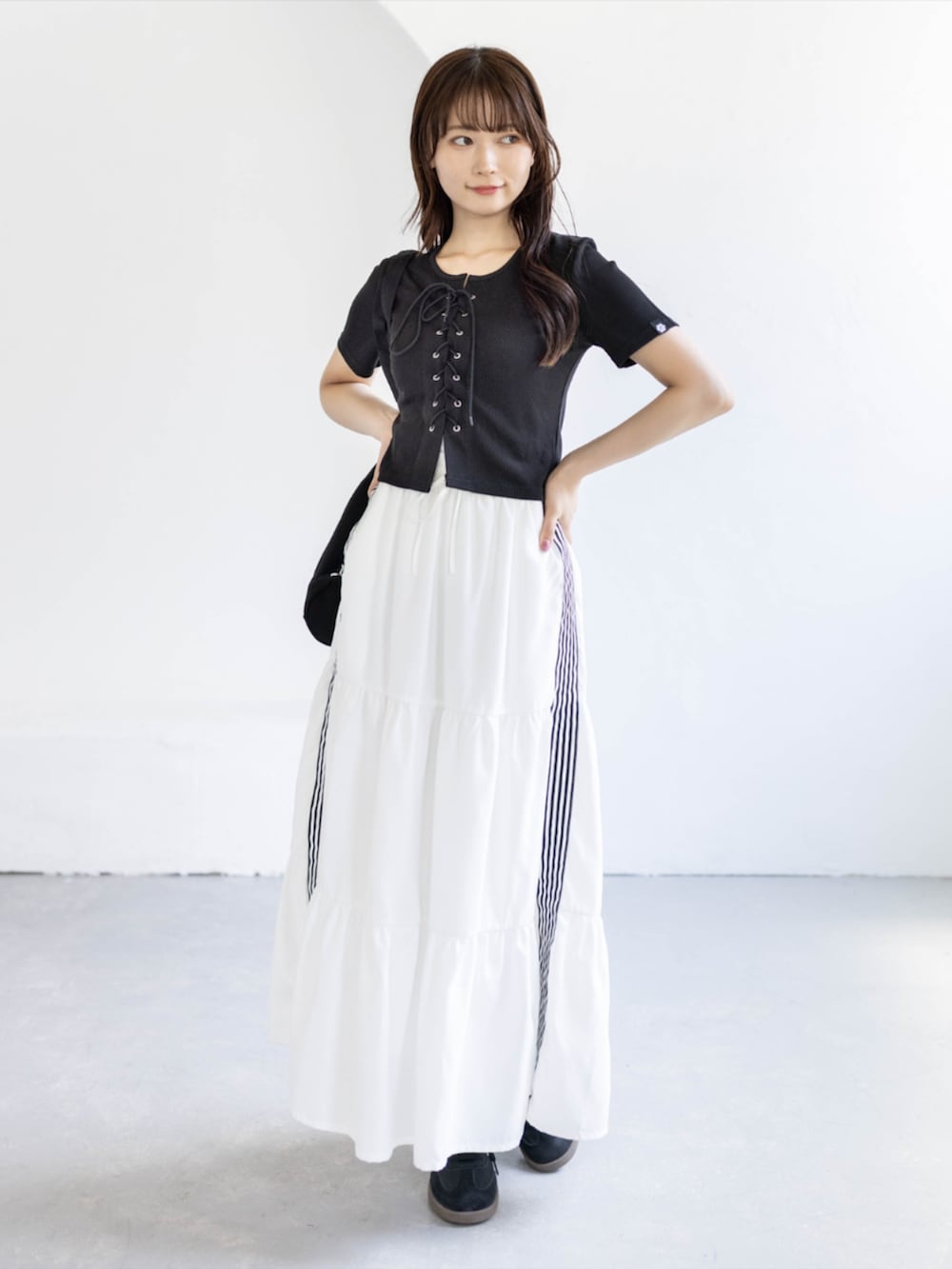 ブラック系のスニーカー、ホワイト系のスカート、ブラック系のTシャツ/カットソーを着用したレディースの夏コーディネートの3枚目の写真