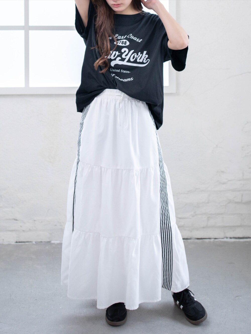ブラック系のスニーカー、ホワイト系のスカート、ブラック系のTシャツ/カットソーを着用したレディースの夏コーディネートの3枚目の写真