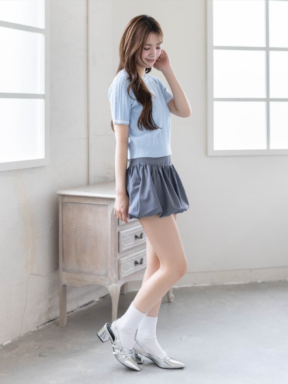 シルバー系のパンプス、グレー系のスカート、ブルー系のニット/セーターを着用したレディースの夏コーディネートの2枚目の写真