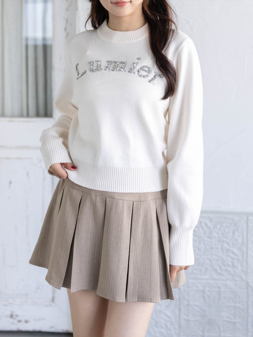 ベージュ系のスカート、イエロー系のパンプス、ホワイト系のニット/セーターを着用したレディースの秋コーディネートの3枚目の写真