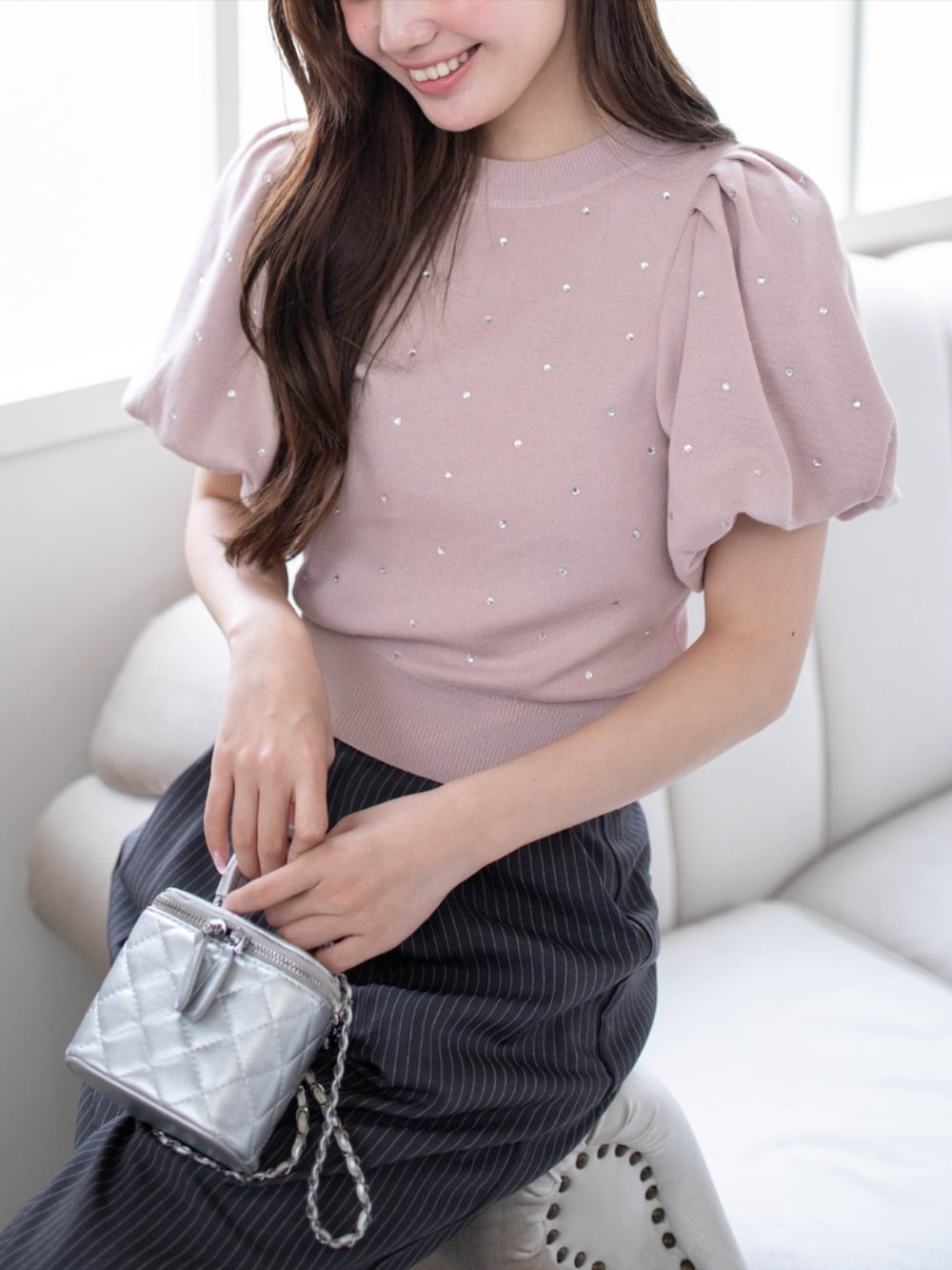 シルバー系のパンプス、グレー系のスラックス、ピンク系のニット/セーターを着用したレディースの夏コーディネートの4枚目の写真