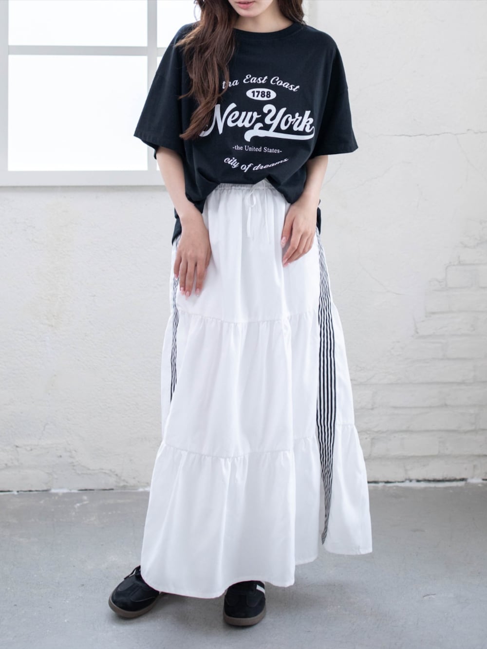 ブラック系のスニーカー、ホワイト系のスカート、ブラック系のTシャツ/カットソーを着用したレディースの夏コーディネートの2枚目の写真