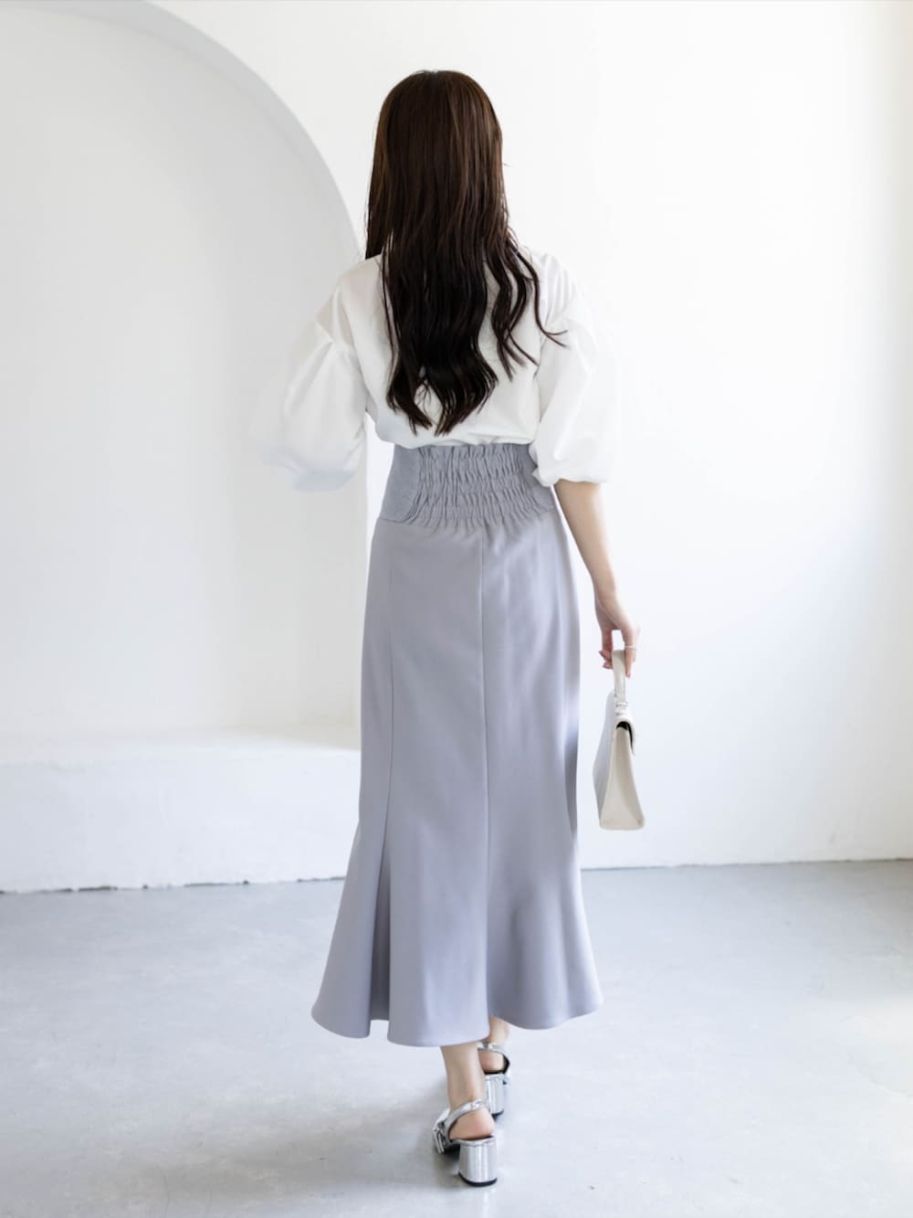 シルバー系のパンプス、ホワイト系のシャツ/ブラウス、グレー系のスカートを着用したレディースの夏コーディネートの2枚目の写真