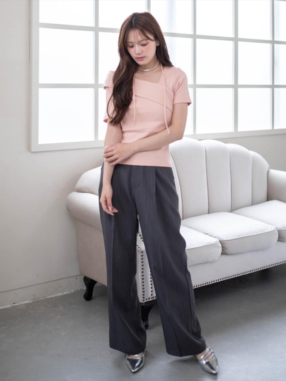 シルバー系のパンプス、グレー系のスラックス、ピンク系のTシャツ/カットソーを着用したレディースの春コーディネートの2枚目の写真