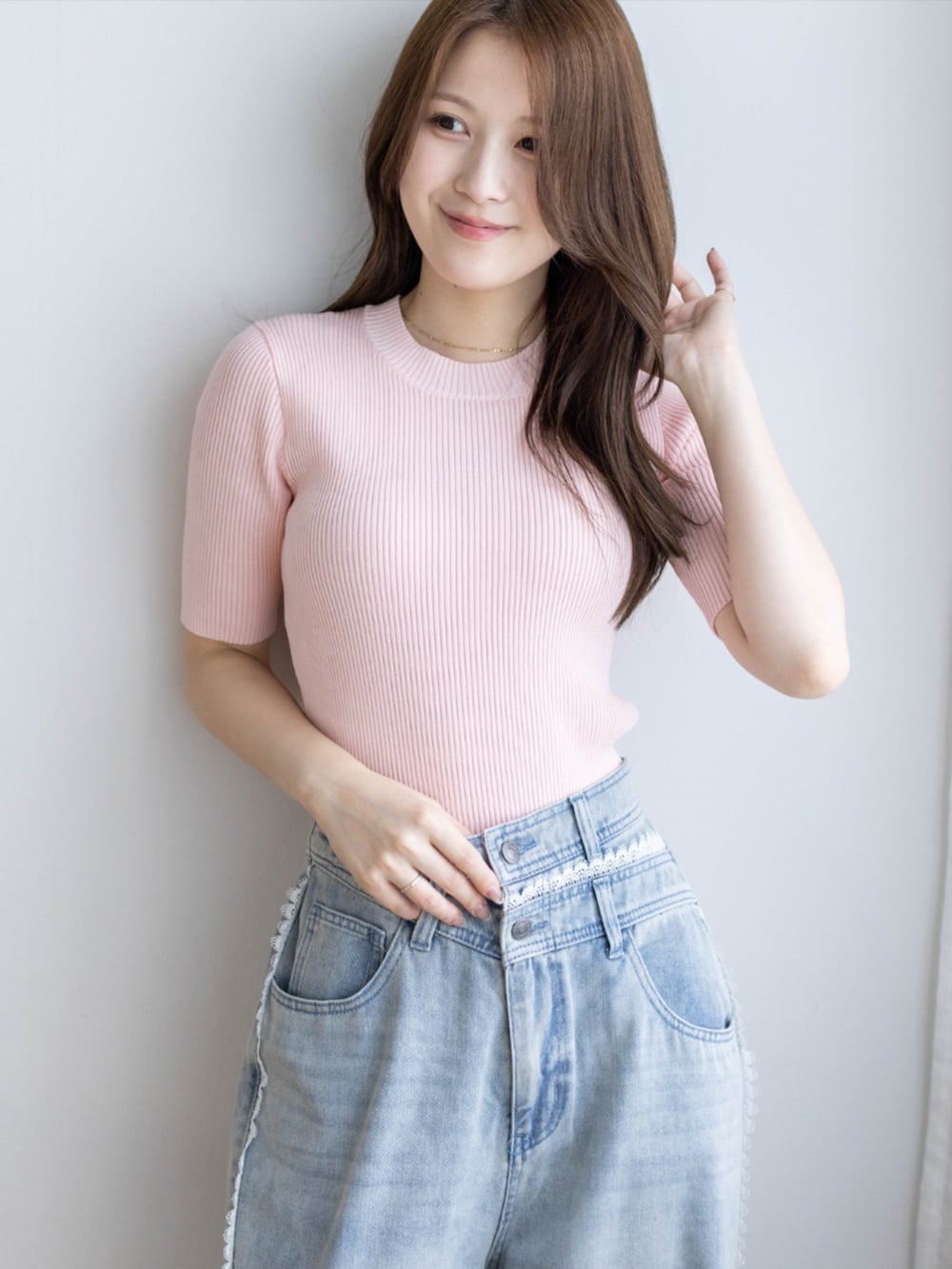 ピンク系のニット/セーター、ブルー系のデニムパンツ、ホワイト系のパンプスを着用したレディースの夏コーディネートの4枚目の写真