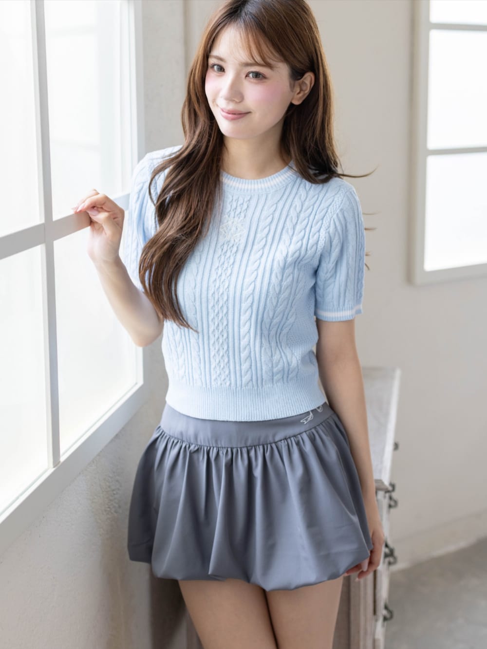 シルバー系のパンプス、グレー系のスカート、ブルー系のニット/セーターを着用したレディースの夏コーディネートの3枚目の写真