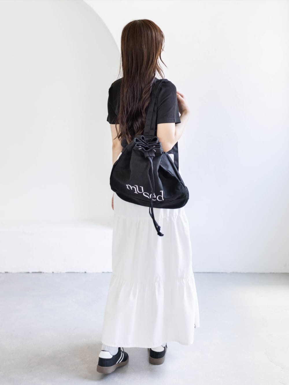 ブラック系のスニーカー、ホワイト系のスカート、ブラック系のTシャツ/カットソーを着用したレディースの夏コーディネートの2枚目の写真